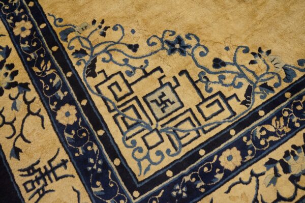 Golden tan rug border with dark blue floral design and blue geometric meander patterns.