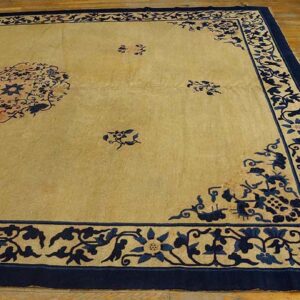 Light beige area rug with a navy blue floral medallion, scatter motifs, and wide border on wood floor.