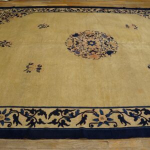 Large tan rug with dark blue floral patterns and a central medallion on hardwood floors.