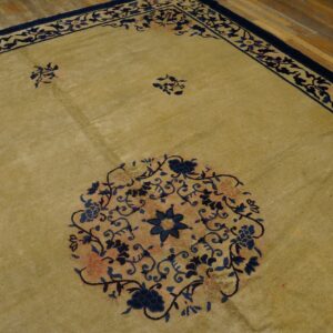 Muted gold rug with deep blue and coral floral medallions and scrolling borders on hardwood flooring.