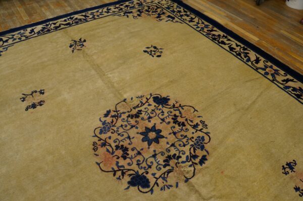 Muted gold rug with deep blue and coral floral medallions and scrolling borders on hardwood flooring.