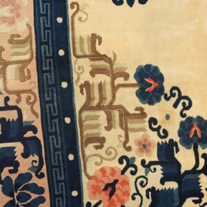 High-pile rug detail with cream, dark blue, coral, and tan floral motifs next to wood flooring.