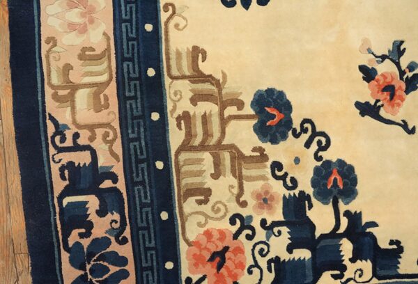 High-pile rug detail with cream, dark blue, coral, and tan floral motifs next to wood flooring.