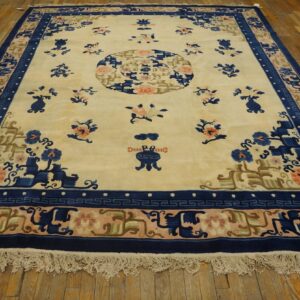 Cream rug featuring a central medallion and scattered floral motifs bordered in navy blue and peach on wood floors.
