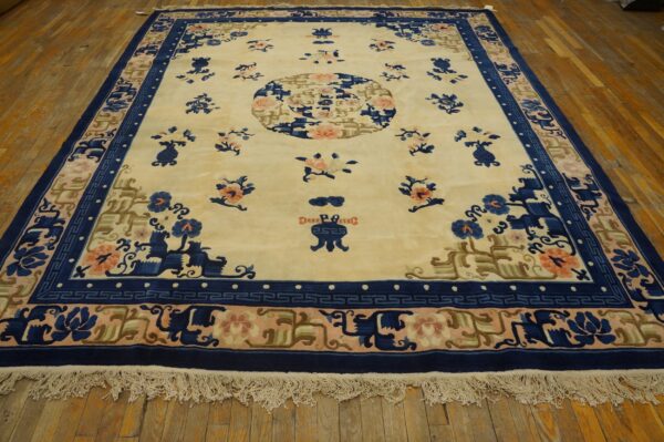 Cream rug featuring a central medallion and scattered floral motifs bordered in navy blue and peach on wood floors.