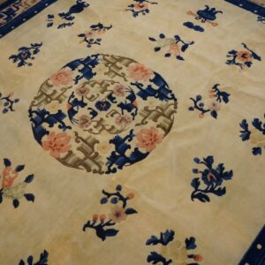 Beige high-pile rug with a blue and pink floral medallion and scattered motifs on wood flooring.
