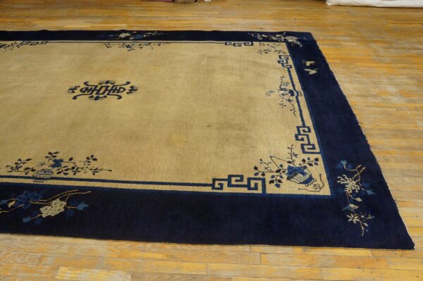 Large tan rug with a wide navy blue border, featuring intricate floral, bird, and geometric patterns.