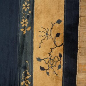 Striped navy blue and golden tan rug features stylized floral vine motifs on wooden flooring.