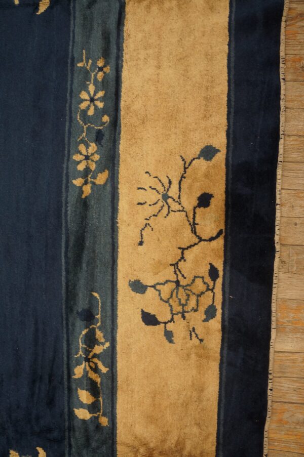 Striped navy blue and golden tan rug features stylized floral vine motifs on wooden flooring.