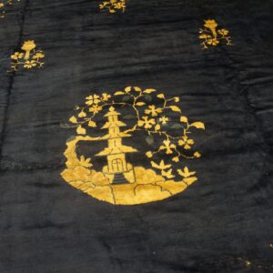 Plush dark blue rug features a detailed golden yellow pagoda and scattered floral motifs.