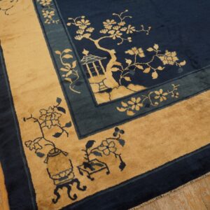 Scenic rug in navy, tan, and teal border details resting on distressed plank hardwood flooring.