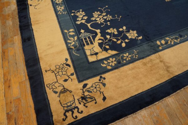 Scenic rug in navy, tan, and teal border details resting on distressed plank hardwood flooring.