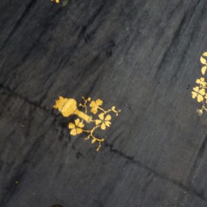 Dark navy rug surface with stylized gold and gray-green floral and botanical patterns.