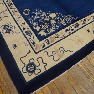Deep blue rug with contrasting cream border featuring detailed floral and symbolic motifs on wood floor.