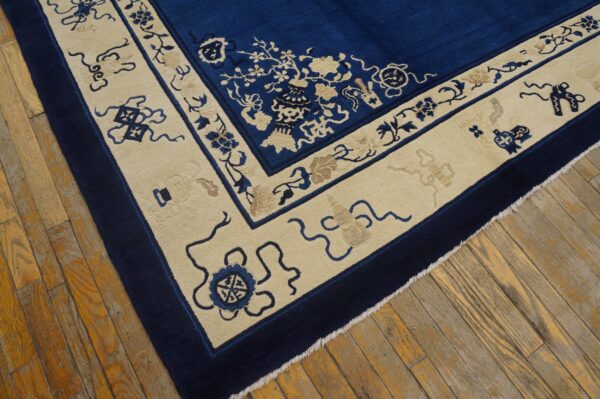 Deep blue rug with contrasting cream border featuring detailed floral and symbolic motifs on wood floor.