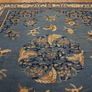 Muted blue rug with tan, navy, and cream floral patterns centered on distressed natural wood flooring.