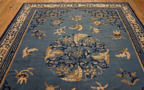 Muted blue rug with tan, navy, and cream floral patterns centered on distressed natural wood flooring.