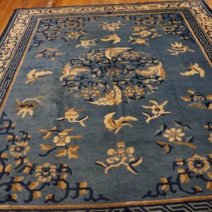 Teal blue rug featuring a central medallion and scattered tan and navy floral motifs on hardwood.