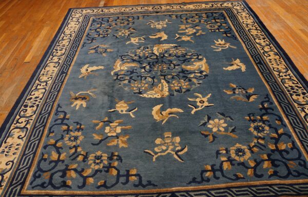 Teal blue rug featuring a central medallion and scattered tan and navy floral motifs on hardwood.