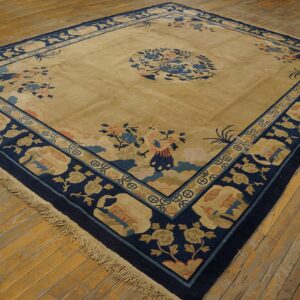 Large beige rug with dark blue borders and light blue and coral motifs rests on rustic wood floors.