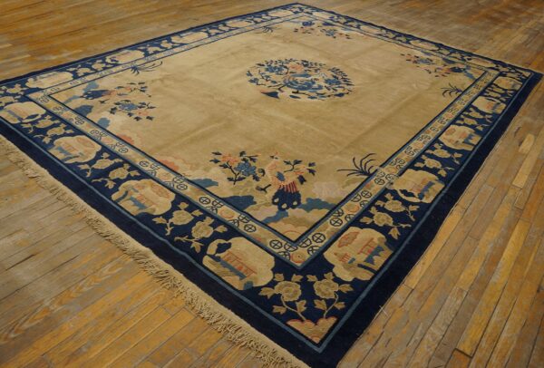 Large beige rug with dark blue borders and light blue and coral motifs rests on rustic wood floors.