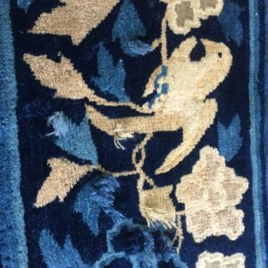 Shaggy rug detail features beige and blue floral patterns, including a bird, on a dark blue ground.