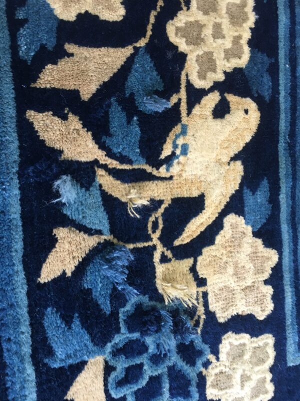 Shaggy rug detail features beige and blue floral patterns, including a bird, on a dark blue ground.