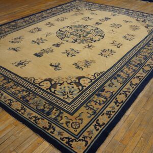 Pale yellow rug with blue floral motifs and a detailed geometric navy border on rustic wood floors.