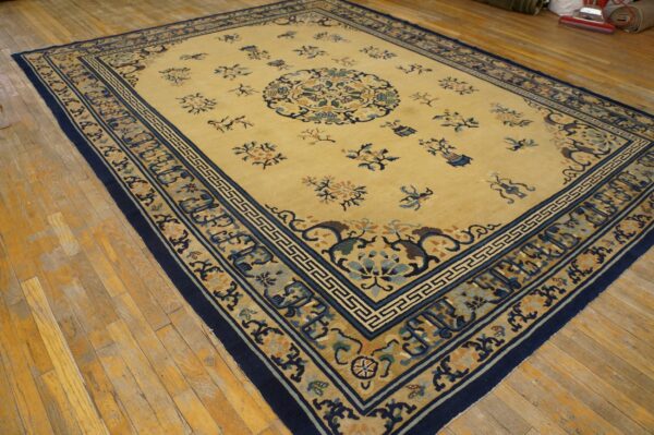Traditional yellow rug featuring blue and tan borders, placed over light colored hardwood flooring.