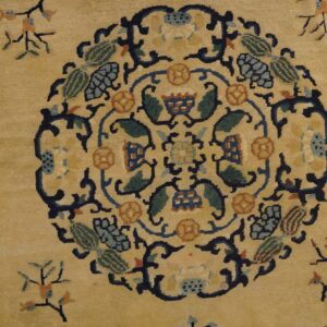 Tan rug with a dense navy, green, and orange stylized floral central medallion pattern.