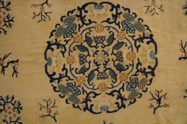 Tan rug with a dense navy, green, and orange stylized floral central medallion pattern.