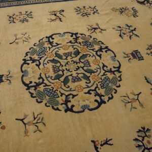 Pale yellow rug featuring a dark blue medallion, scattered floral sprigs, and a complex fretwork border pattern.