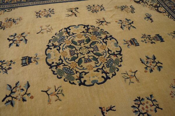 Pale yellow rug featuring a dark blue medallion, scattered floral sprigs, and a complex fretwork border pattern.