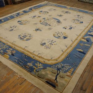 Cream and blue scenic pattern rug with a bamboo border rests on distressed wood flooring.
