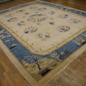 Ivory rug with a wide blue landscape border and tan bamboo framing on aged hardwood flooring.