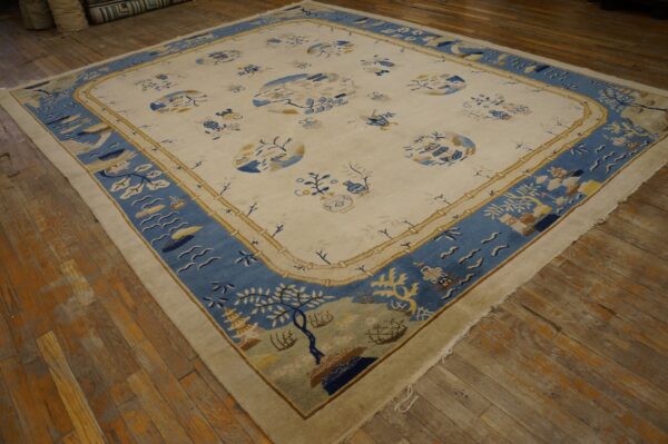 Ivory rug with a wide blue landscape border and tan bamboo framing on aged hardwood flooring.