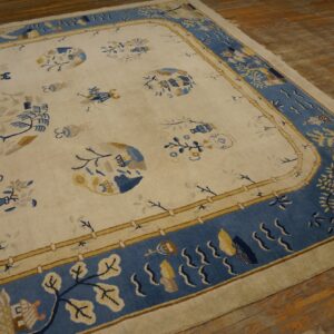 Cream rug with blue and yellow stylized motifs and a broad blue ornamental border on wood flooring.