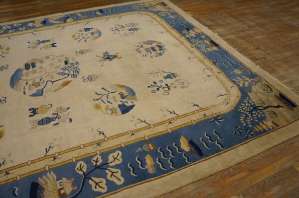 Cream rug with blue and yellow stylized motifs and a broad blue ornamental border on wood flooring.