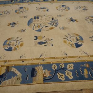 Cream rug with blue and gold scattered botanical and medallion designs, framed by a wide blue pictorial border.