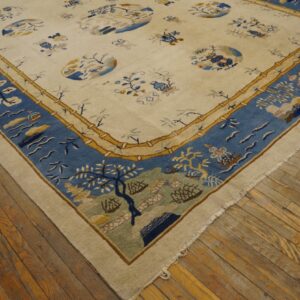 Cream-colored rug featuring a detailed blue border and gold bamboo trim, laid on distressed wood planks.