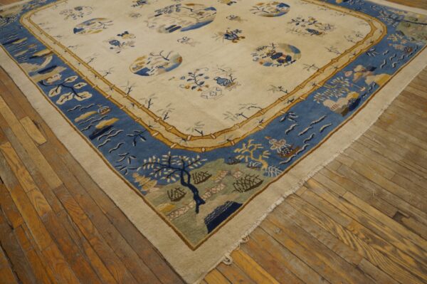 Cream-colored rug featuring a detailed blue border and gold bamboo trim, laid on distressed wood planks.