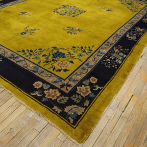 High-pile chartreuse rug featuring blue and taupe floral borders lays across worn plank wood flooring.