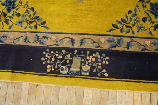 Chartreuse and navy rug border with floral and vase motifs lies on weathered wood floorboards.