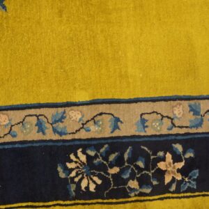 A chartreuse rug field and detailed blue floral borders sit on distressed wood floorboards.
