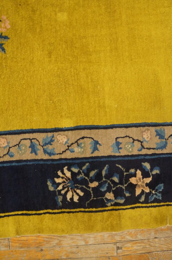 A chartreuse rug field and detailed blue floral borders sit on distressed wood floorboards.