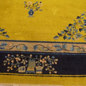 A bright yellow rug field features blue and pink florals leading to a complex navy blue border design.