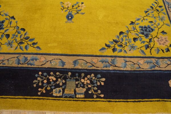 A bright yellow rug field features blue and pink florals leading to a complex navy blue border design.