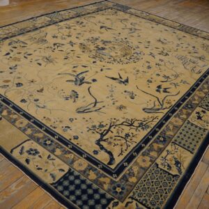 Light yellow rug featuring pictorial blue birds and cherry blossoms, set on worn hardwood flooring.