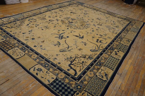 Light yellow rug featuring pictorial blue birds and cherry blossoms, set on worn hardwood flooring.