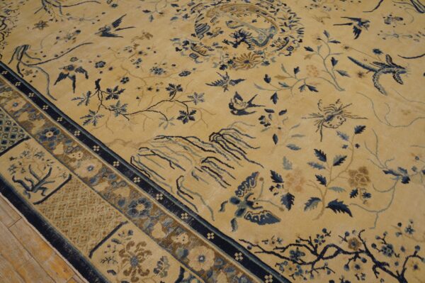 Low-pile golden rug with blue birds and branches, showing a patterned border on light wood floorboards.
